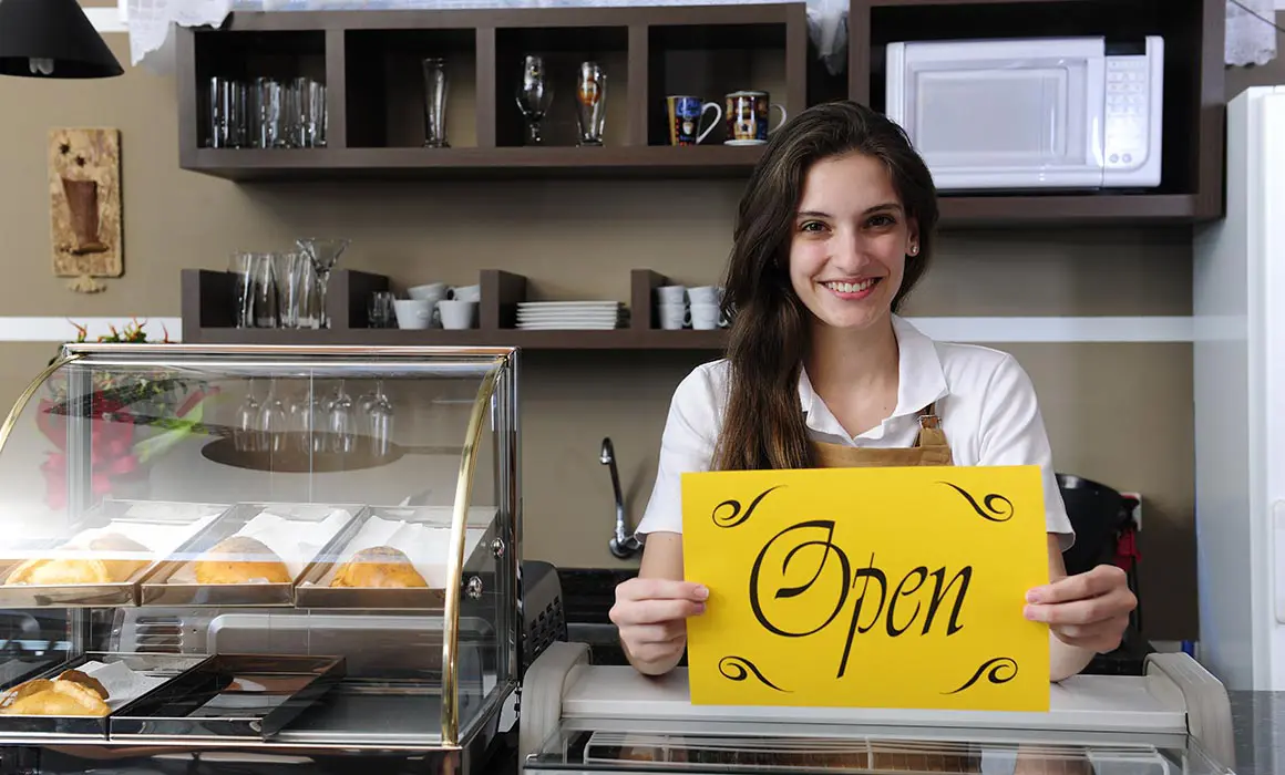 Small business: Happy owner or waitress of a cafe showing open sign