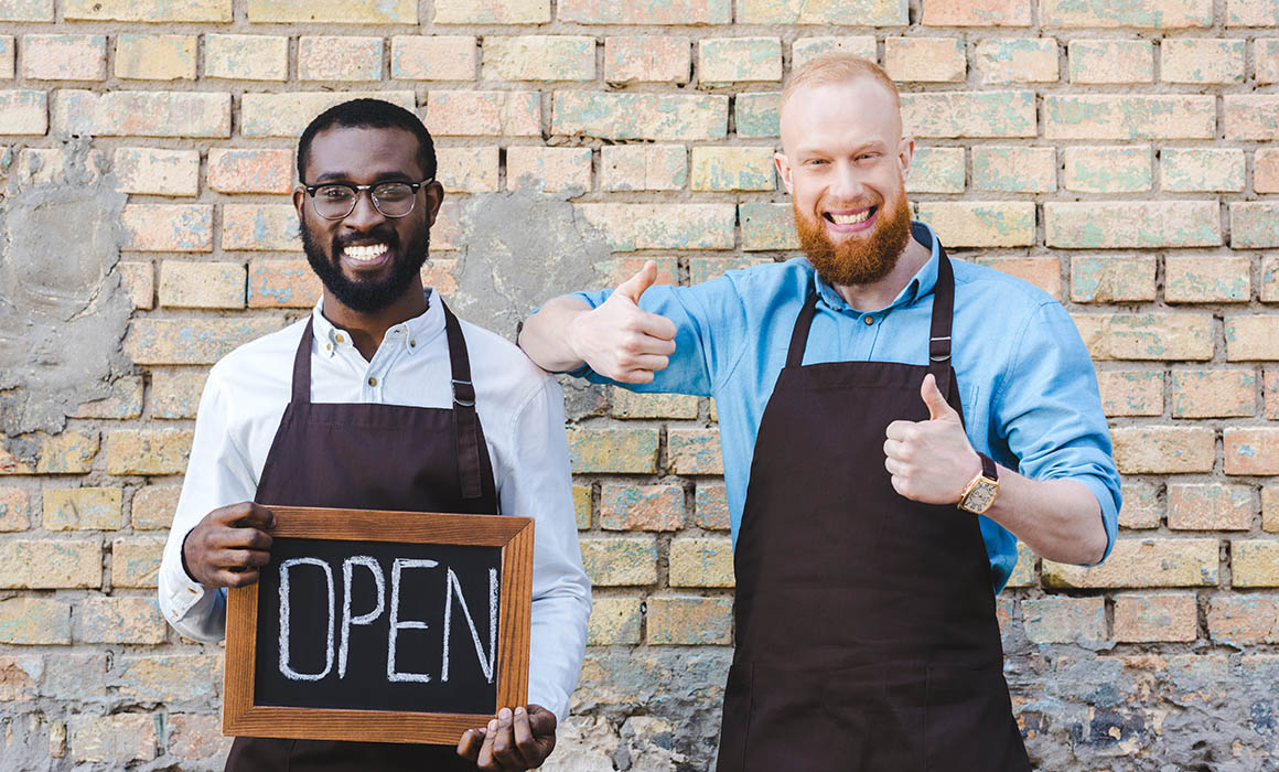 Image of two business owner in Alexandria VA holding OPEN sign