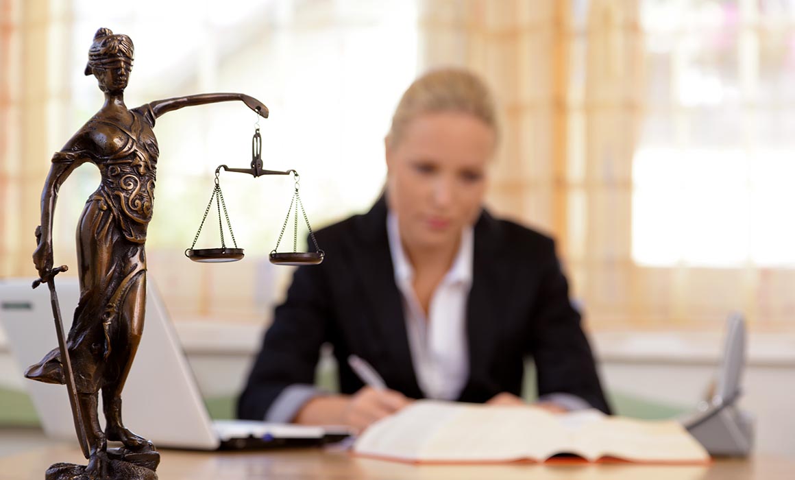 A young lawyer is sitting at her desk in the office.